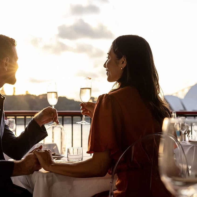 Couple dining at Mrs Macqueries Chair in Sydney, drinking wine with views of the harbour