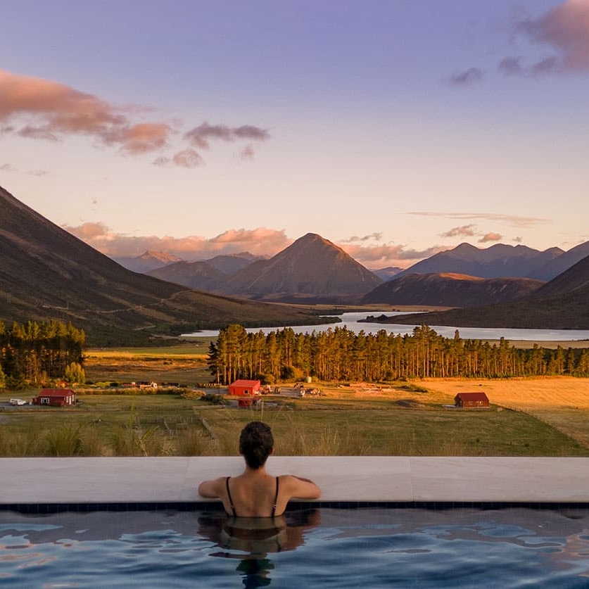 Woman looking out over a pristine valley from the pool at Flockhill, New Zealand