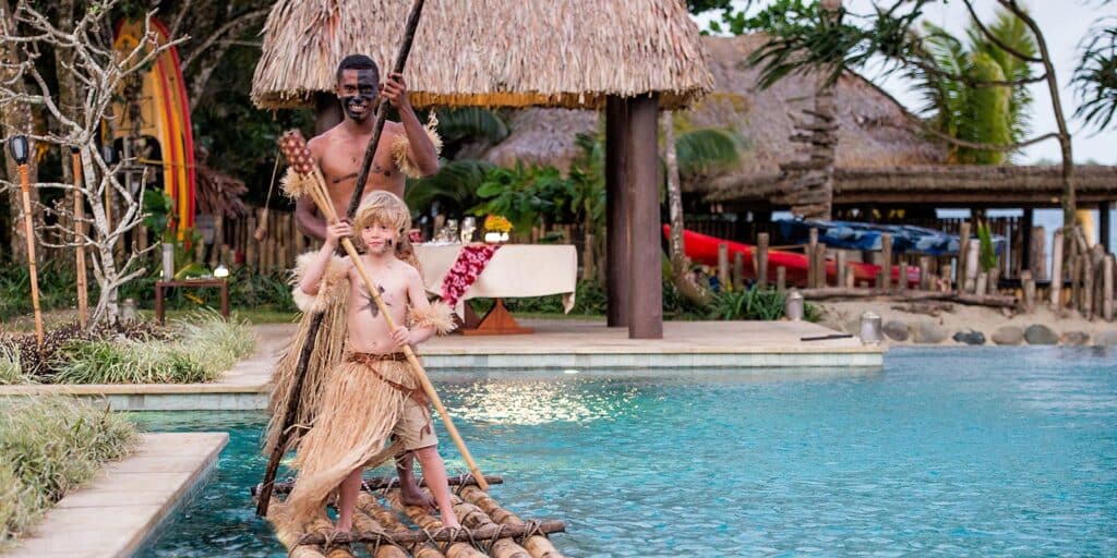 Child and local Fijian host paddling in the pool at Nanuku Resort