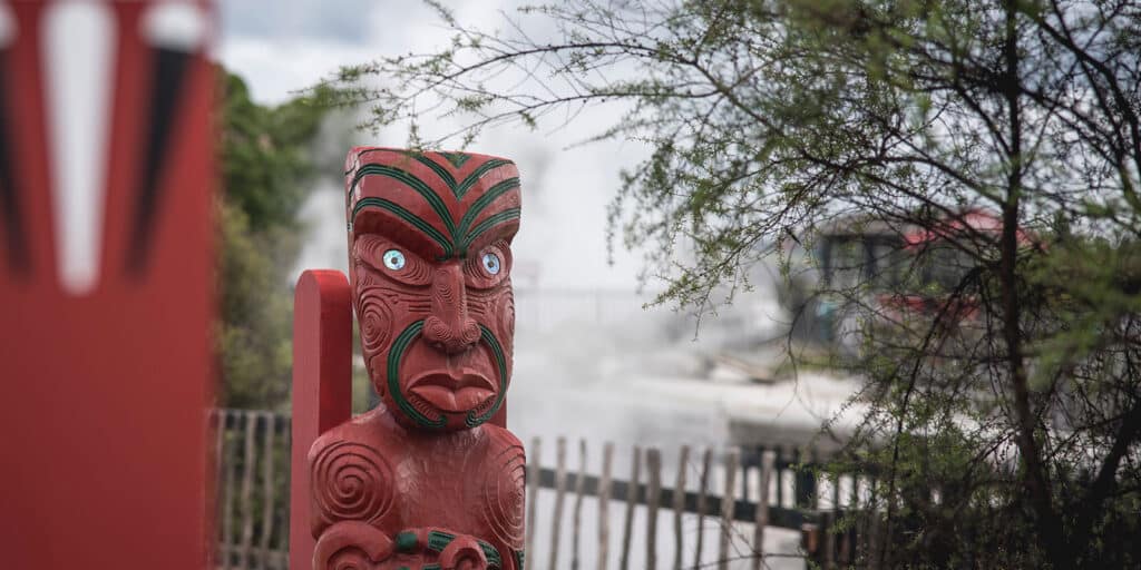 Maori carving with steam from geothermal pools in the background - Rotorua, New Zealand