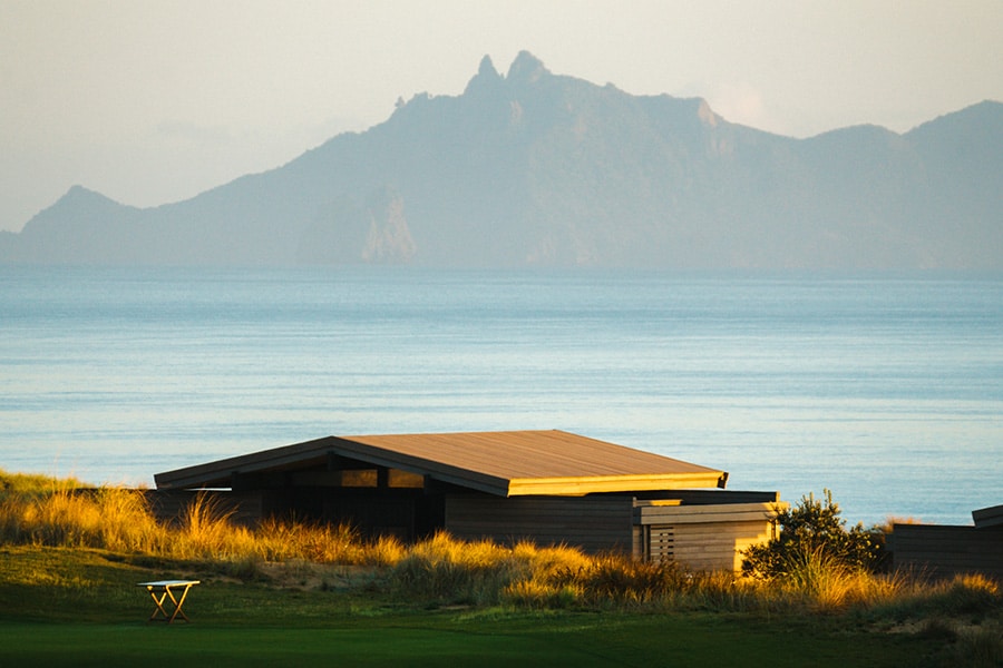View of an Ocean Cottage from the 1st hole at Te Arai Links, with views of the ocean and mountains in the distance