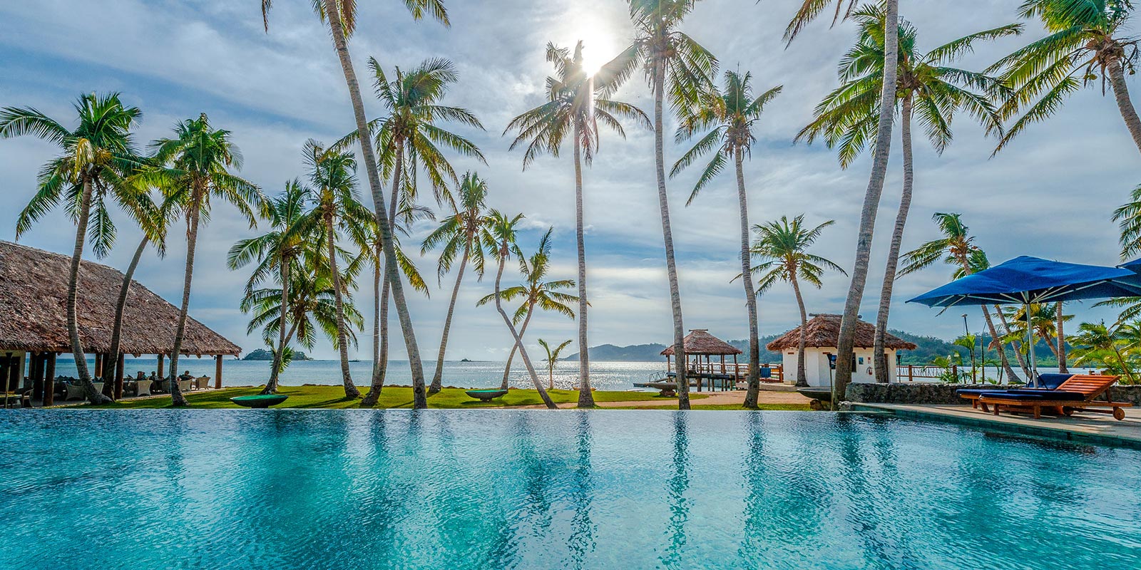 View of the Horizon Pool at Tropica Resort Fiji, with palm trees and ocean in the distance