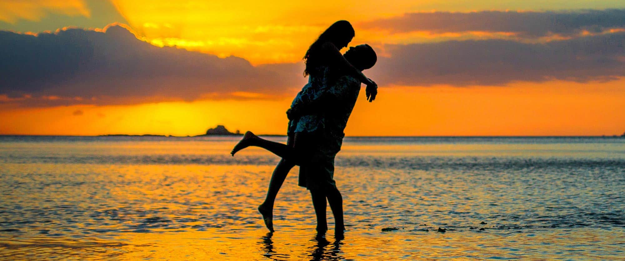 Couple silhouetted on the beach at sunset at Tropica Resort Fiji