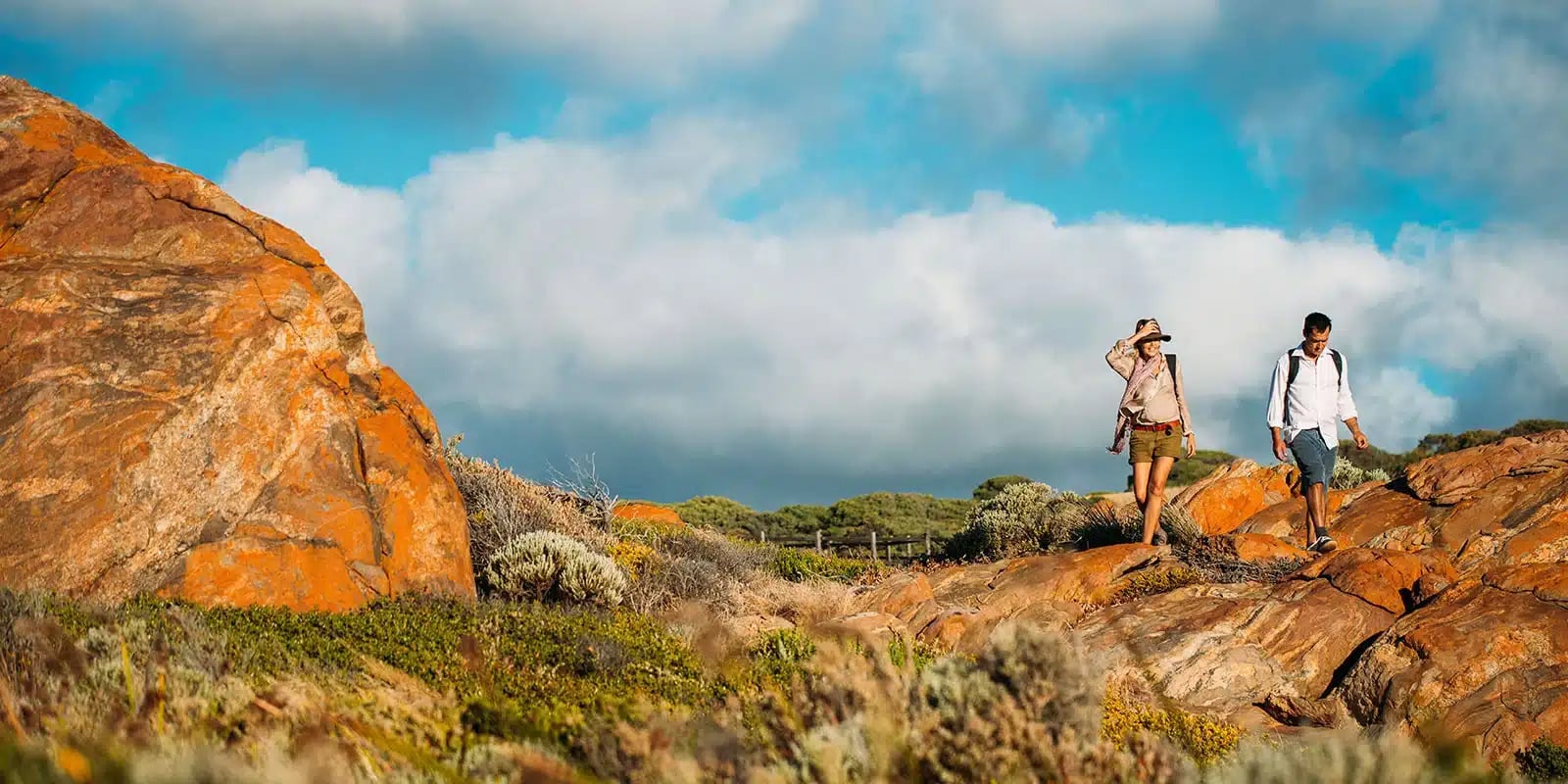 Couple walking on the vibrant orange Wyadup Rocks, part of the Cape to Cape Track in Australia