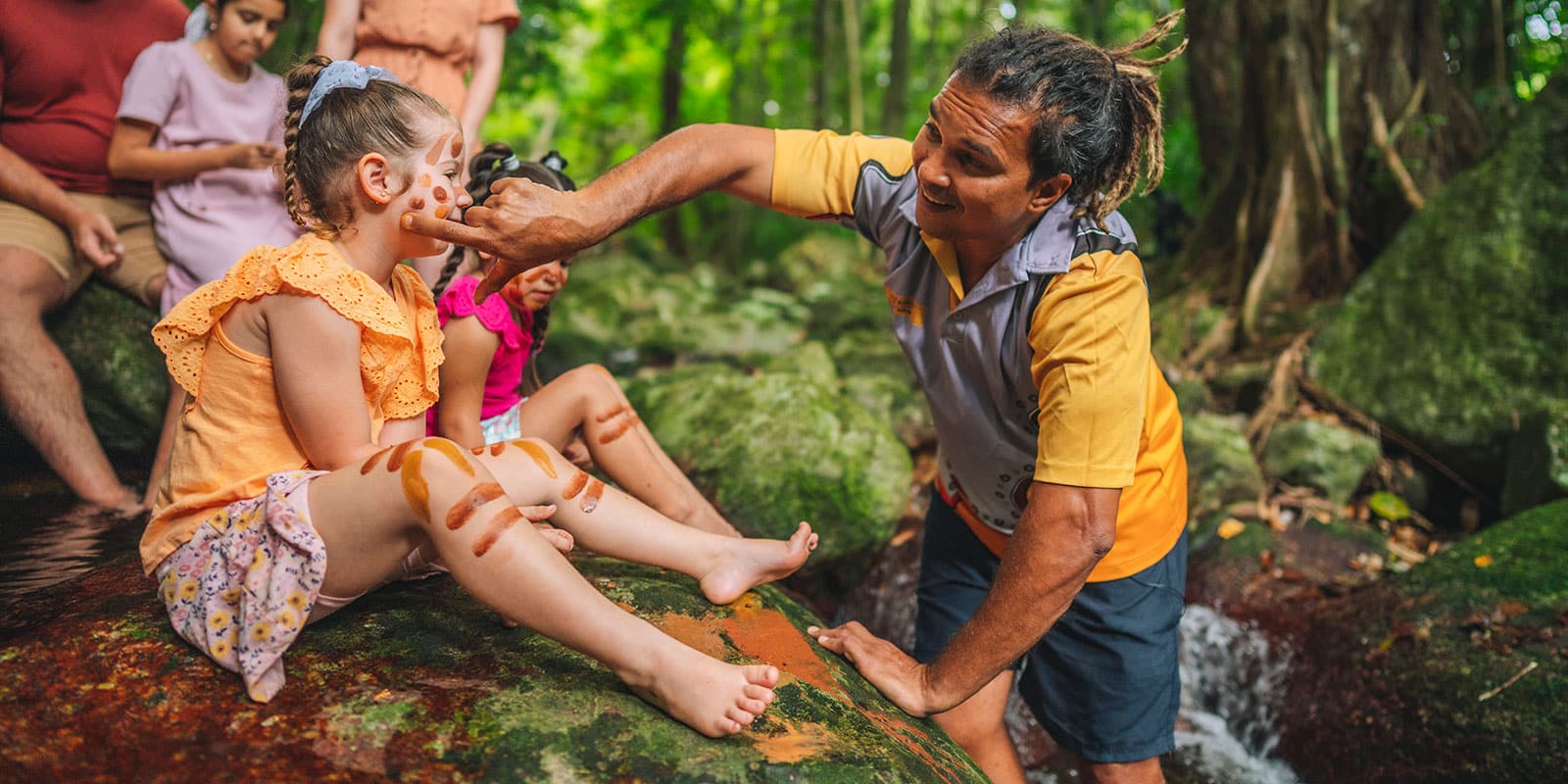 Guide painting a child's face with ochre in the Daintree Rainforest, Australia
