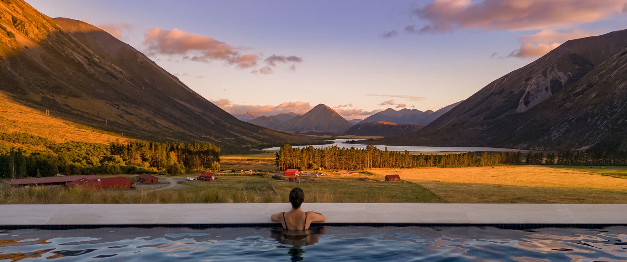 Woman looking out over a pristine valley from the pool at Flockhill, New Zealand