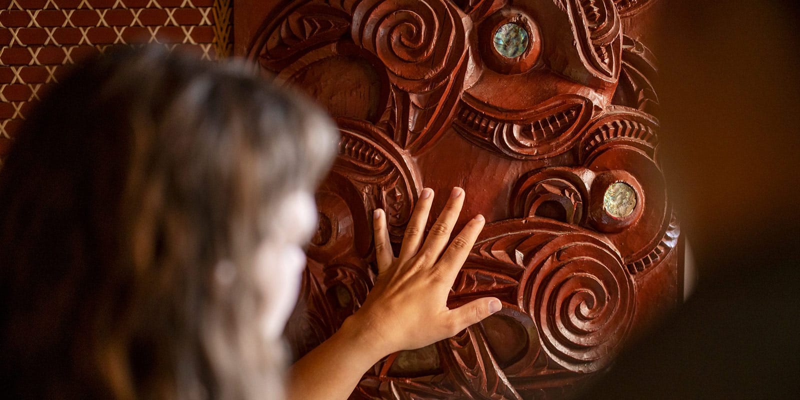 Woman touching a Maori carving at Te Puia geothermal and cultural park - Rotorua, New Zealand